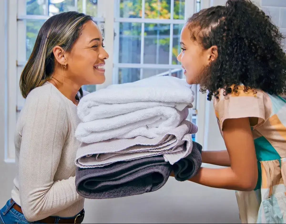 Professional laundry service - person holding neatly folded, clean clothes from NoScrubs laundry delivery